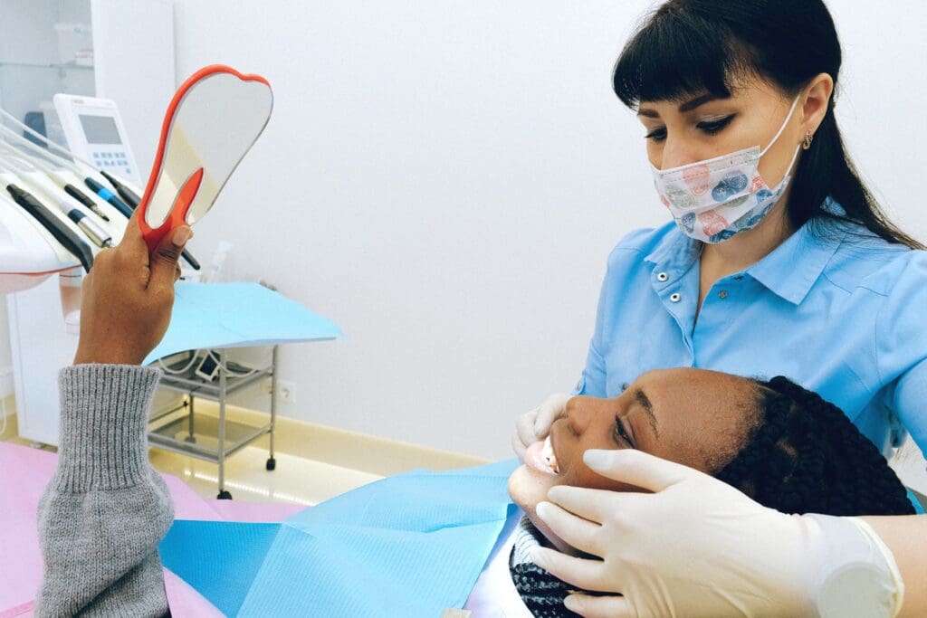 Dentist and patient smiling with teeth and looking in the mirror