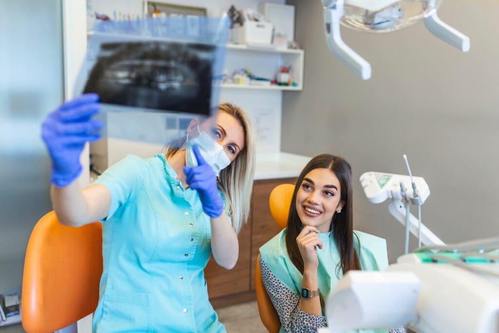 Patient and dentist examining teeth X-ray