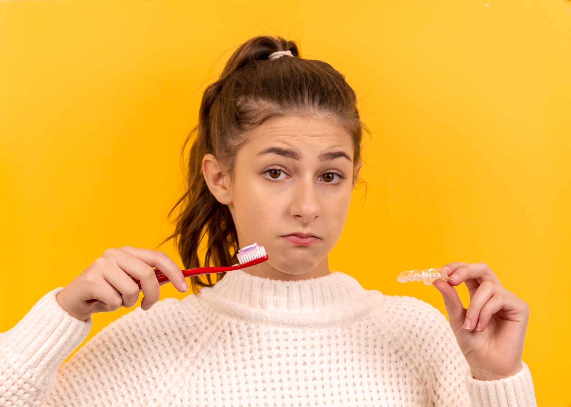 Woman holding toothbrush and Invisalign aligners