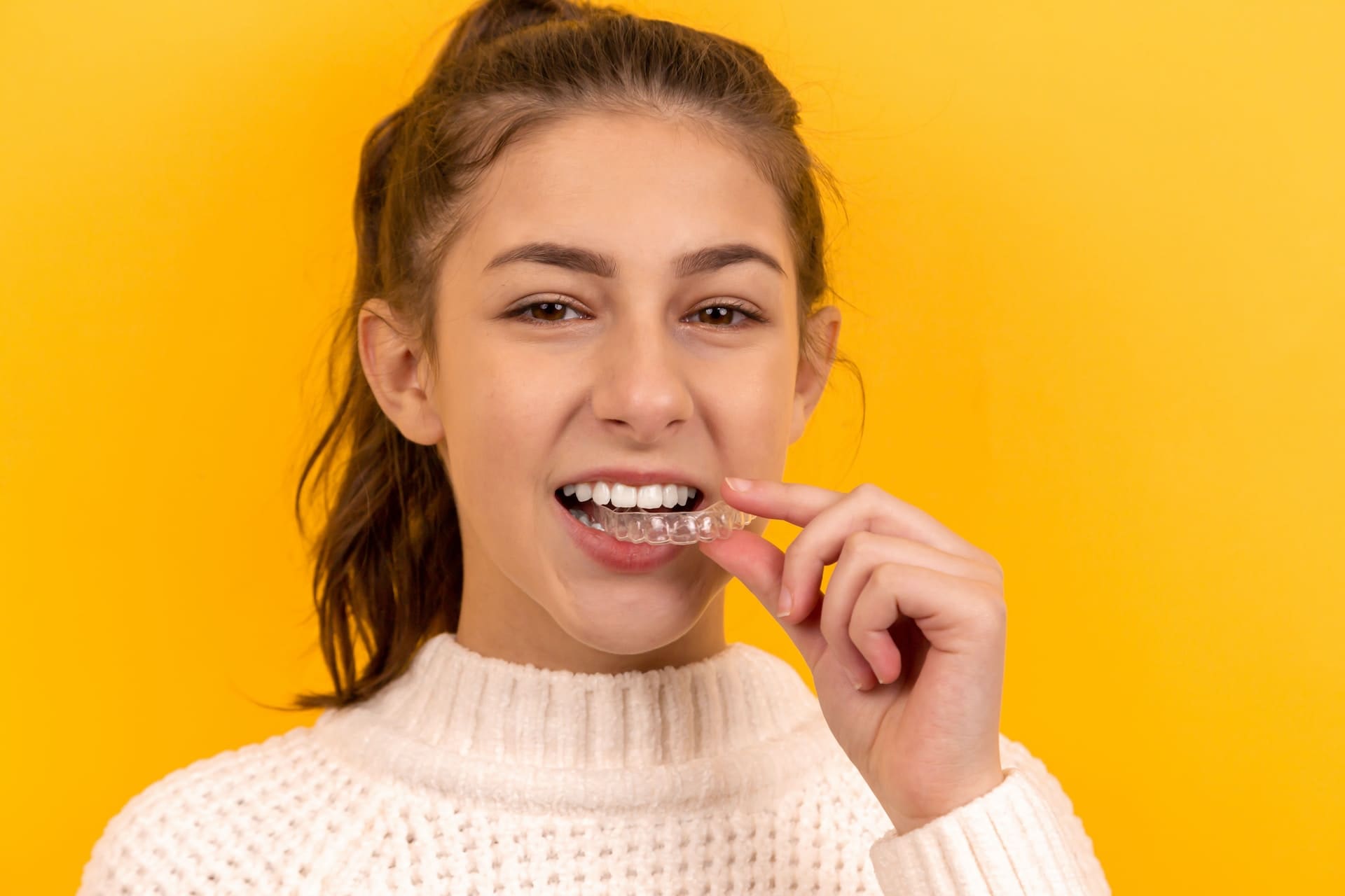 Girl holding Invisalign aligners