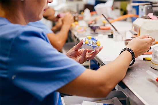 A dental lab technician making a prosthetic