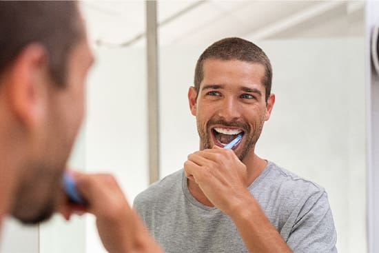 Patient in Danvers brushing their teeth to avoid dental emergencies