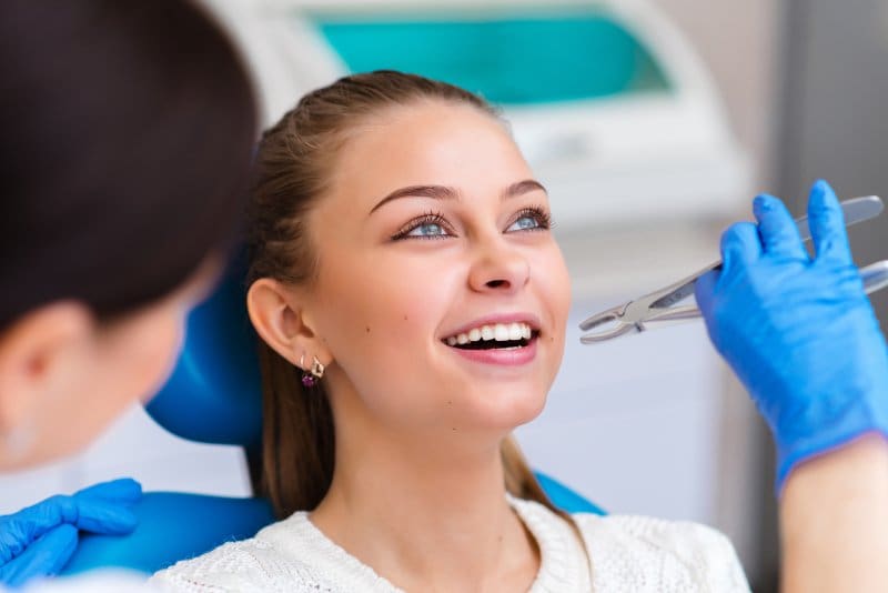 Dental forceps preparing to grab a patient’s tooth