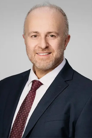 Profile image of Dr. Konstantinos Vazouras smiling in a suit and tie.