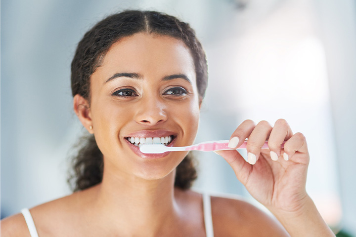 Closeup of woman smiling while brushing her teeth.