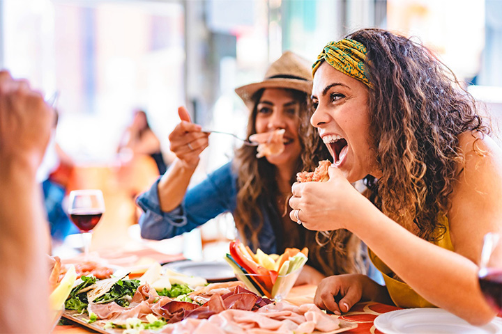 Friends smiling while enjoying meal in restaurant.