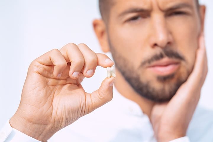 A man holding his extracted tooth after surgery