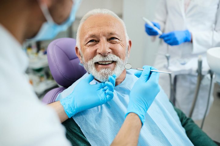 An older man receiving treatment from his dentist.