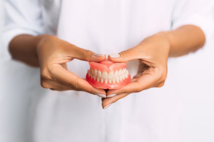 Lady presents viewer with dentures.