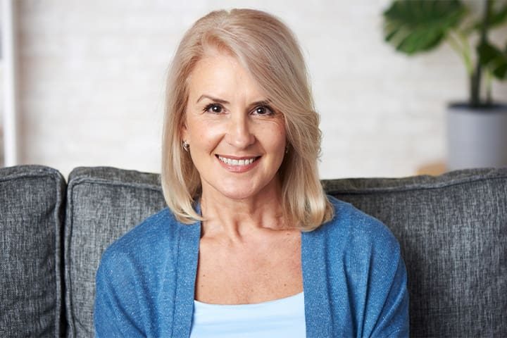 Older woman smiling on a couch after a root canal
