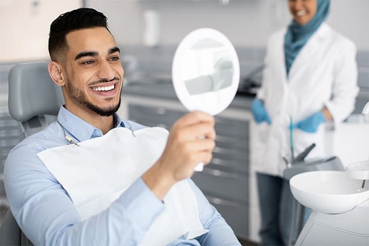 Man looking at his new veneers and smiling